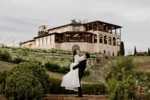 Newlywed couple embracing outside a Tuscan-inspired vineyard wedding venue